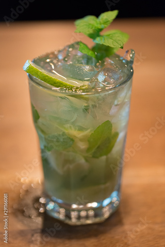 Refreshing mint cocktail mojito with rum and lime, cold drink or beverage with ice on white wooden background, top view