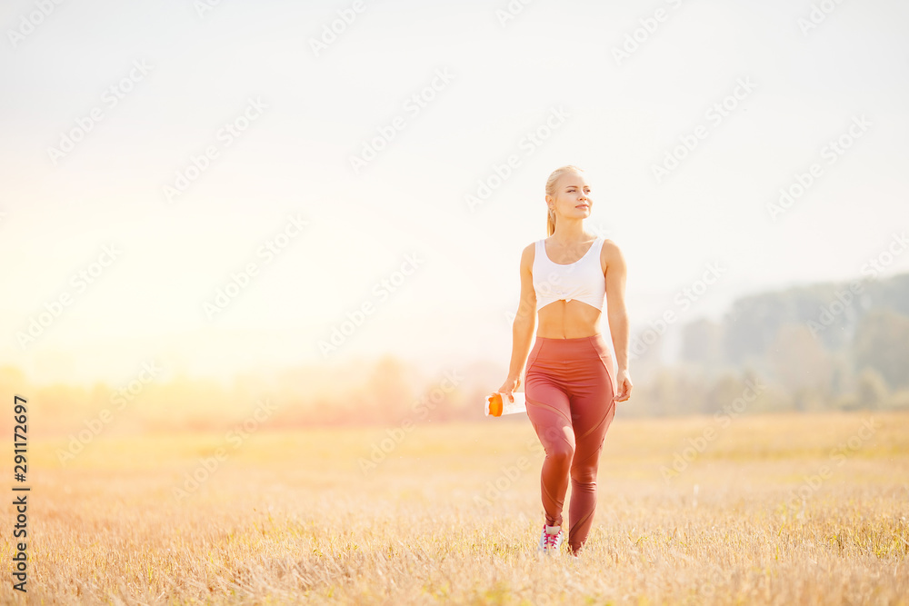 Happy young blonde girl holds water bottle in park, concept thought about state of health Happy young blonde girl holds water bottle in park, concept thought about state of health