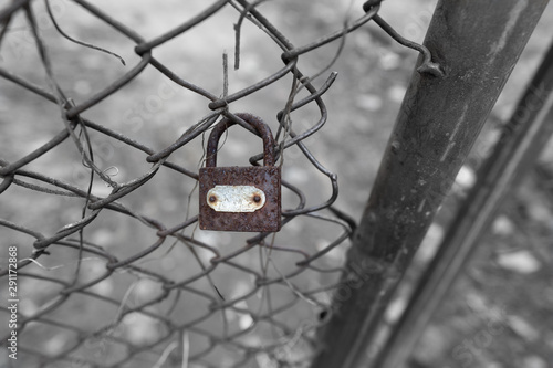 old grunge and rusty padlock on metal mesh fence texture background