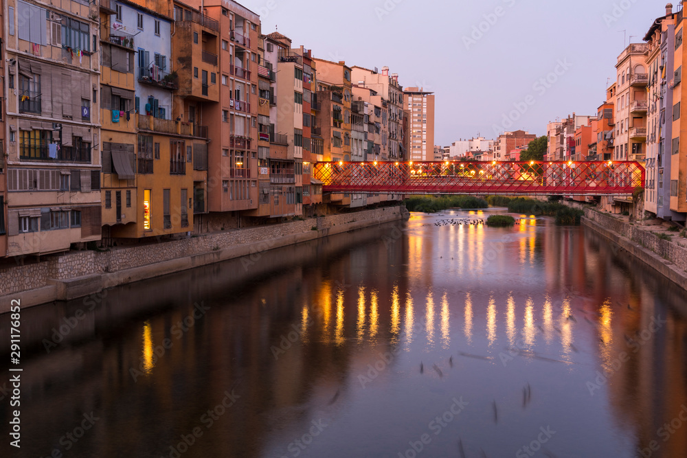 Naklejka premium Colorful yellow and orange houses reflected in water river Onyar, in Girona, Catalonia, Spain.