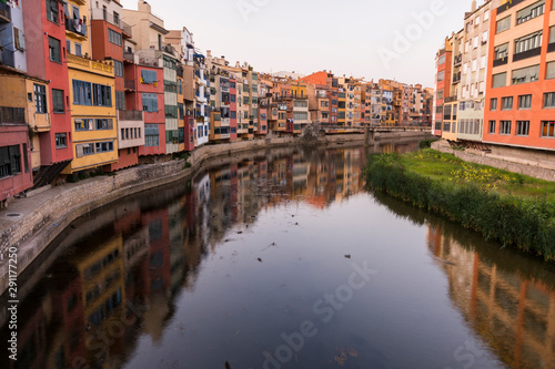 Colorful yellow and orange houses reflected in water river Onyar, in Girona, Catalonia, Spain.