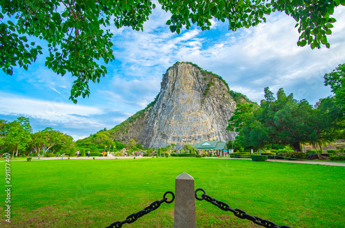 Pattaya, Thailand - July 2019 :Tourist travelling and taking photo with beautiful Buddha Mountain (Khao Chee chan) during cloudy day. Khao chee chan the largest buddha carved in the world.. photo