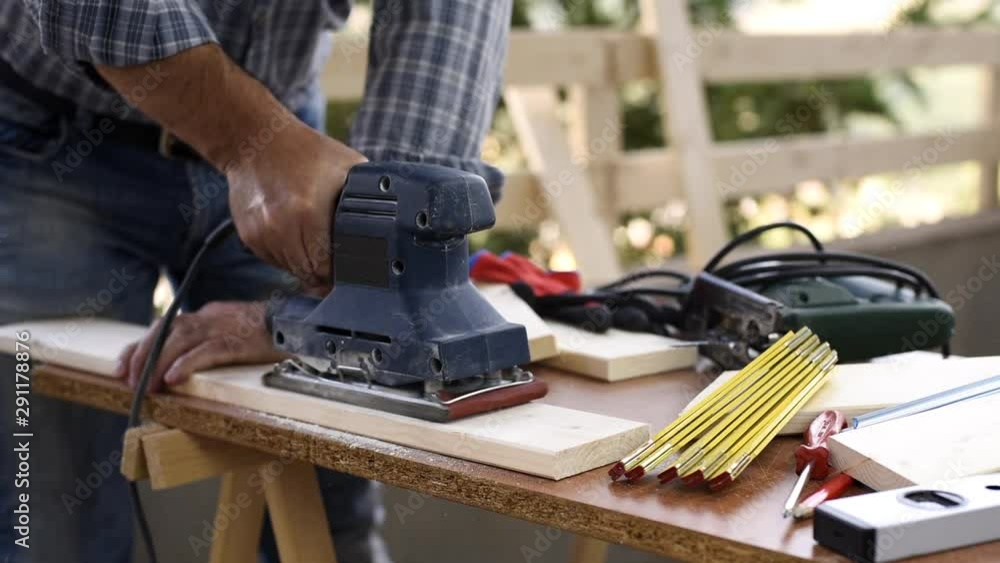 Adult carpenter craftsman with electric sander smoothes a wooden table. Housework do it yourself. Footage. Adult carpenter craftsman with electric sander smoothes a wooden table. Housework do it yourself. Footage.