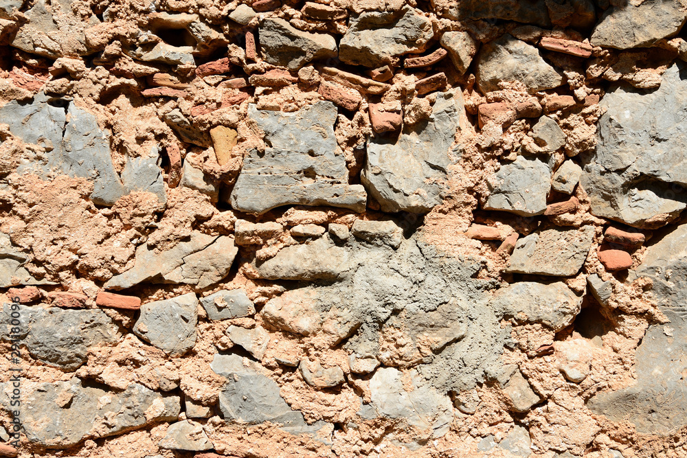 Fragment of an ancient wall illuminated by the bright sun close-up. Stone wall background. Fragment of an ancient wall illuminated by the bright sun close-up. Stone wall background.