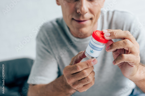 cropped view of man in t-shirt looking at medical cannabis