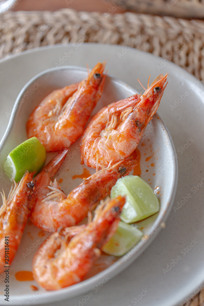 Shrimps shelled fried in garlic and oil, served on white plate garnished with lime green. Shrimps shelled fried in garlic and oil, served on white plate garnished with lime green.