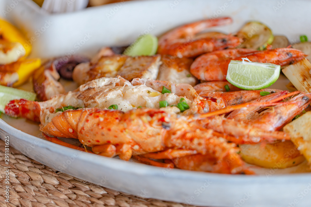 Grilled seafood with lobster, shrimp, squid and fish, accompanied by various vegetables.