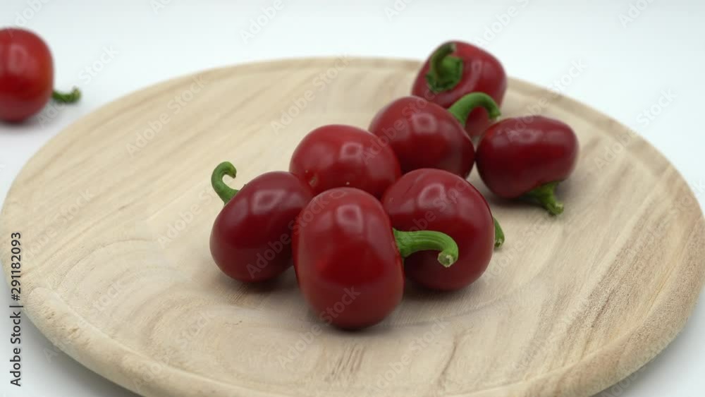 Red hot chili peppers on white background. Woman's hand throwing small fresh chili peppers on plate. Chili peppers falling on plate. Ingredient for hot spice, 4K video shoot Red hot chili peppers on white background. Woman's hand throwing small fresh chili peppers on plate. Chili peppers falling on plate. Ingredient for hot spice, 4K video shoot