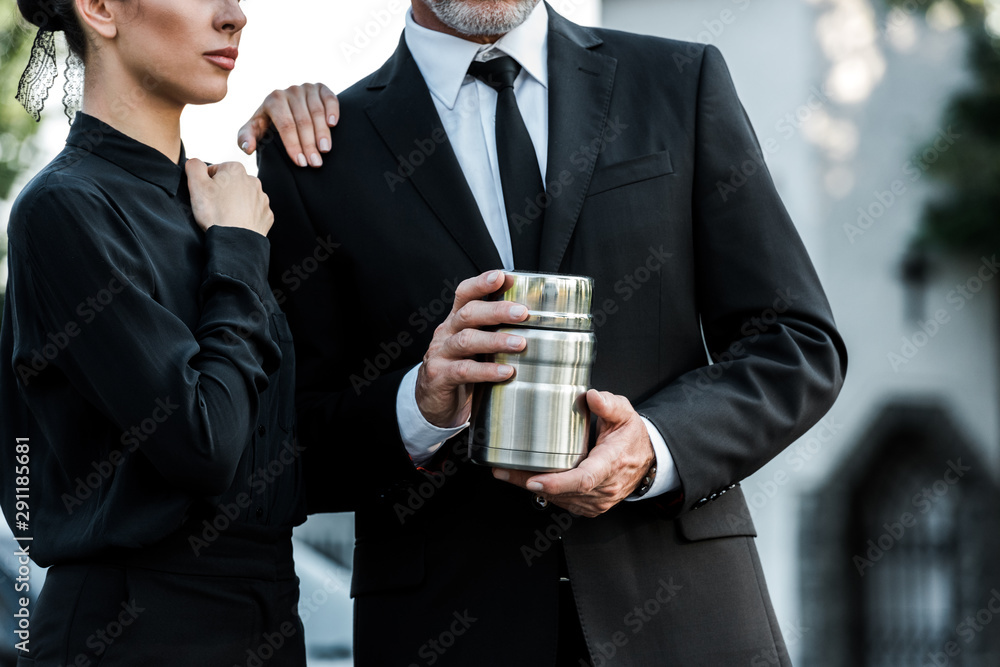 cropped view of woman standing near bearded man holding cemetery urn cropped view of woman standing near bearded man holding cemetery urn