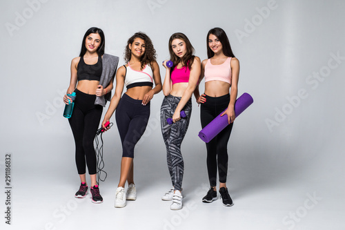 Four fitness girls in sportwear holding exercises equipment isolated on white background