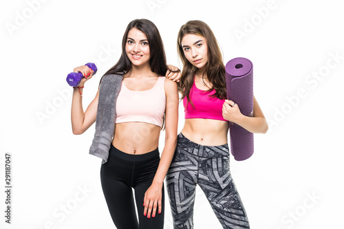 Sporty young woman lifts heavy dumbbell, works on muscles, wears headband, casual purple t shirt, cheerful girl holds fitness mat.