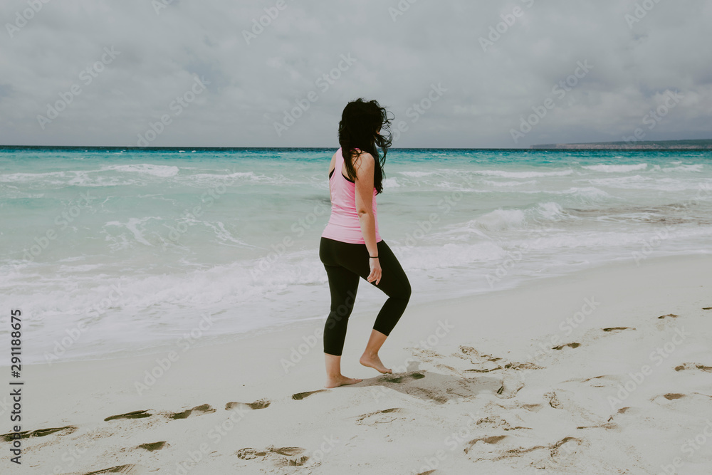 Brunette woman taking a walk on the beach in a cloudy day Brunette woman taking a walk on the beach in a cloudy day