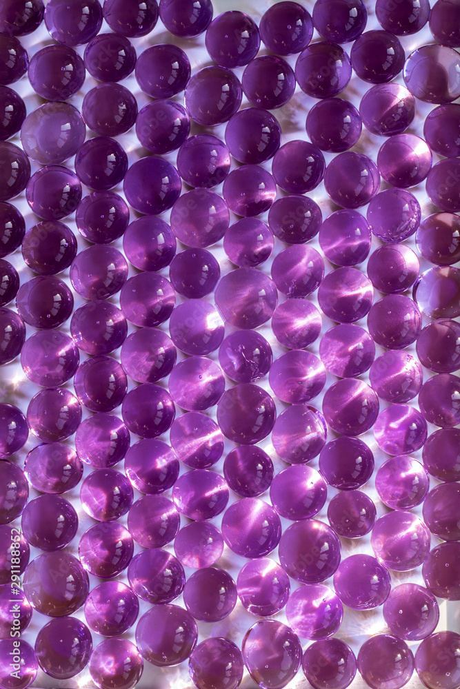 Abstract background of purple gel balls on a wet white surface
