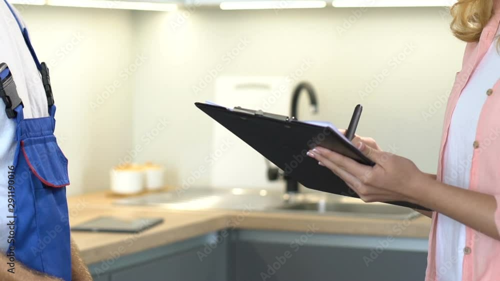 Lady signing papers and returning them to male plumber after repair, services Lady signing papers and returning them to male plumber after repair, services
