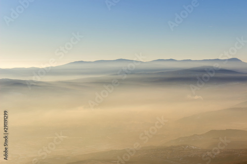Soft  colorful  misty mountain layers and fields covered by golden fog during sunset