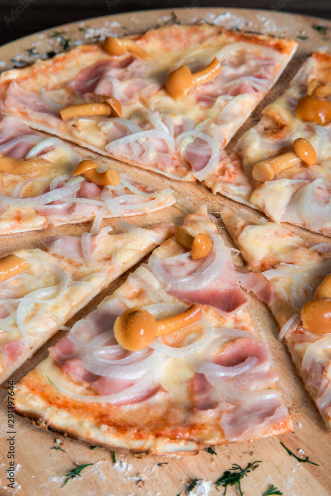 pizza with ham, mushrooms and onions on a wooden plate pizza with ham, mushrooms and onions on a wooden plate