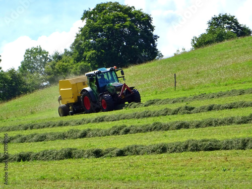 tractor mowing grass on a sloping meadow in midsummer