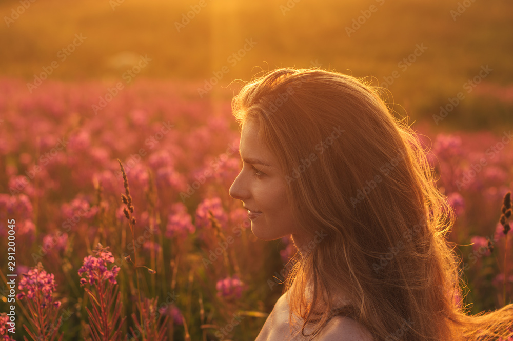 Side portrait of girl staying among blooming Sally field Side portrait of girl staying among blooming Sally field