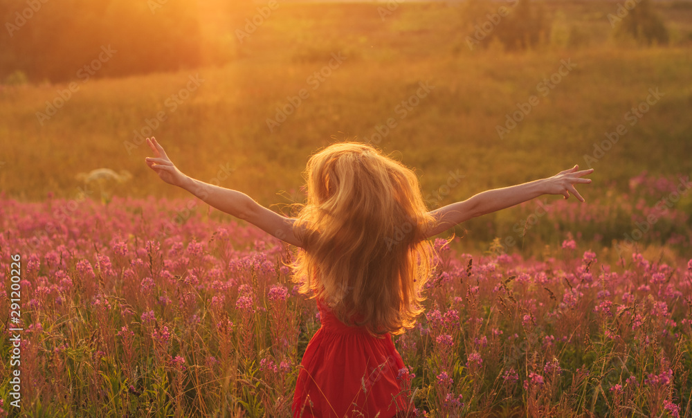 Dancing and jumping girl with hands up in red dress among blooming Sally field Dancing and jumping girl with hands up in red dress among blooming Sally field