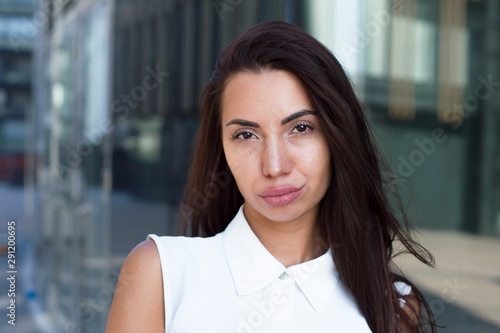 Portrait of a sexy hot girl with freckles and big botox lips. Pigmentation, skin defects. Young beautiful glamouros business woman outdoor looking at camera with a displeased serious reproachful look. photo