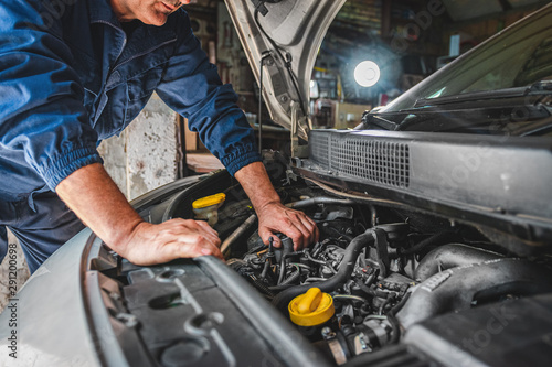 Car service worker checking oil and repairing motor at auto service cente