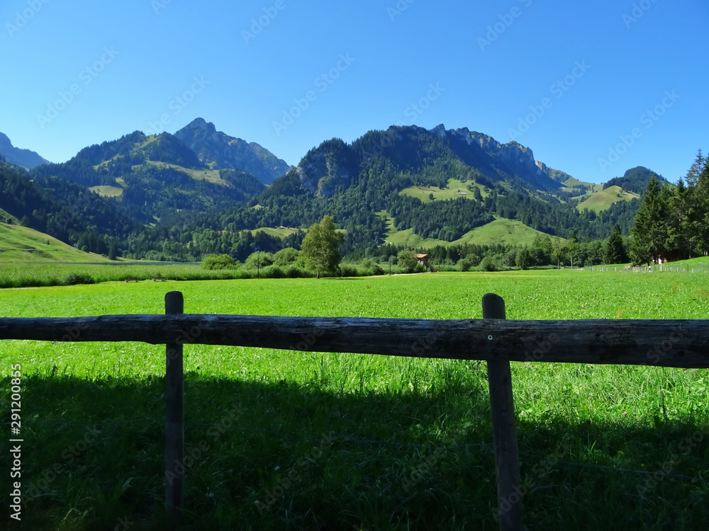 Panoramic view of a landscape with mountains and wooden fence in the foreground