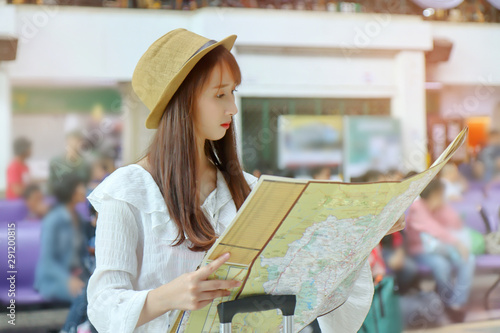 Female tourist uses her hands to open the tourist map to see route inside the railway station