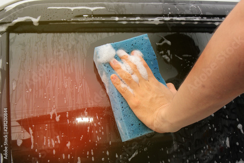 Car washing by using sponge and cleaner at glass door.