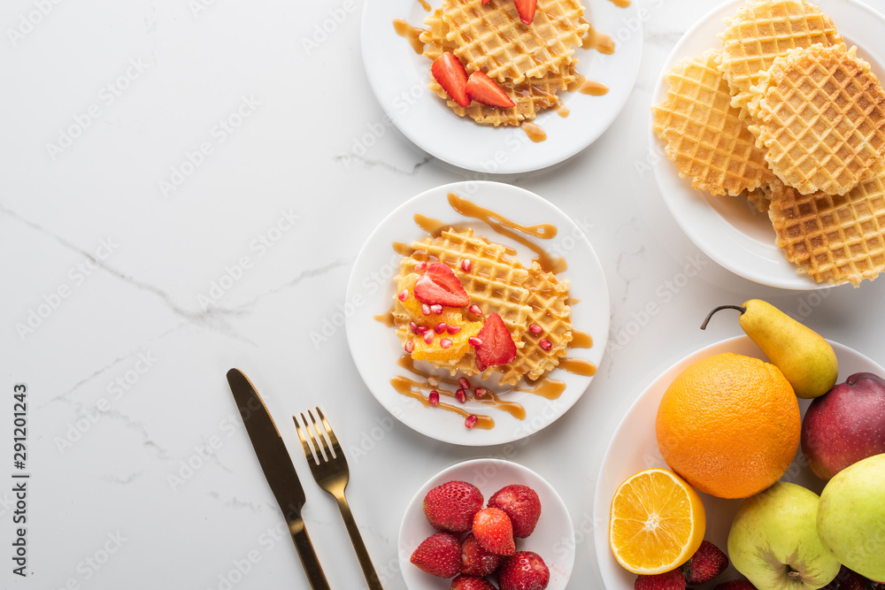 waffles with strawberries on a white plate on a white background with golden fork and knife waffles with strawberries on a white plate on a white background with golden fork and knife