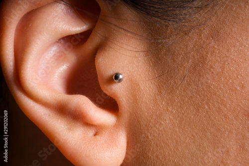 female ear tragus piercing close-up detail photo