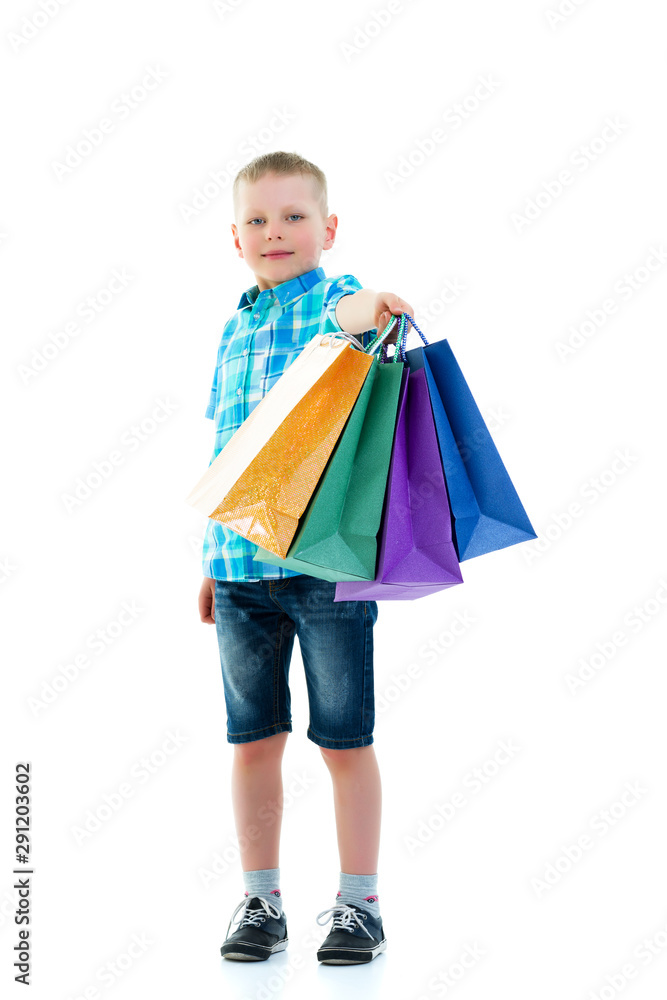 Little boy waving multicolored paper bags. He goes shopping