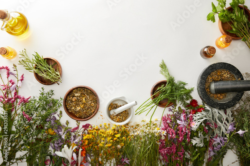 top view of mortars and pestles with herbal blends near flowers on white background photo