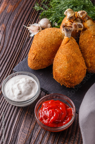 fried chicken leg in batter, red and white sauce on a dark surface photo