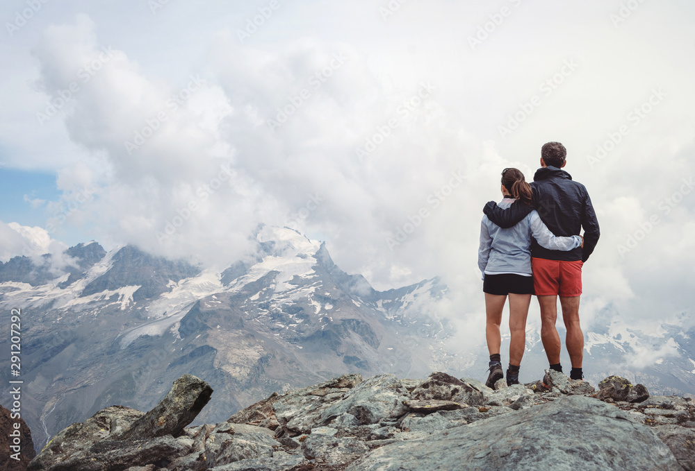 Couple embracing while looking at the mountains, italian Alps. Italy