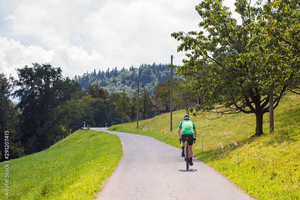 Obraz premium Cyclist riding a bike along a mountain asphalt road