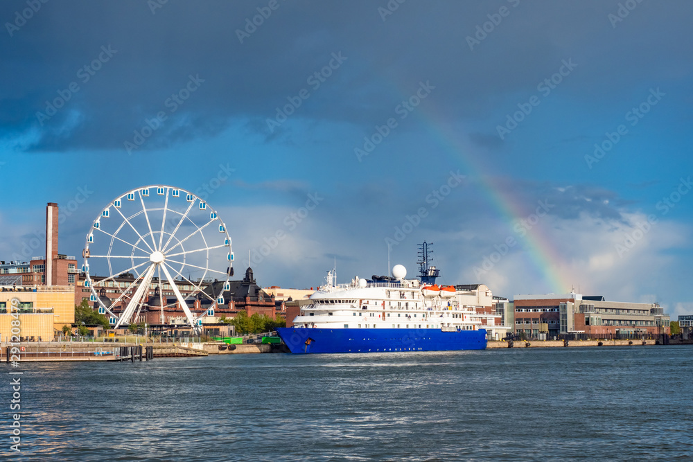 Helsinki. Finland. Liner on a background of a ferris wheel. Rainbow. Ferris wheel on the promenade. Traveling by ship to Finland. Helsinki panorama. Liner at the city harbor. Tourism in Finland