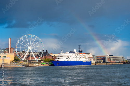 Helsinki. Finland. Liner on a background of a ferris wheel. Rainbow. Ferris wheel on the promenade. Traveling by ship to Finland. Helsinki panorama. Liner at the city harbor. Tourism in Finland © Grispb