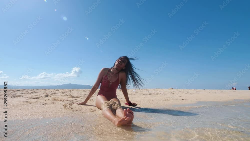 A cheerful girl sit on seashore and throw fine sands up in the air and laughing. A cheerful girl sit on seashore and throw fine sands up in the air and laughing.