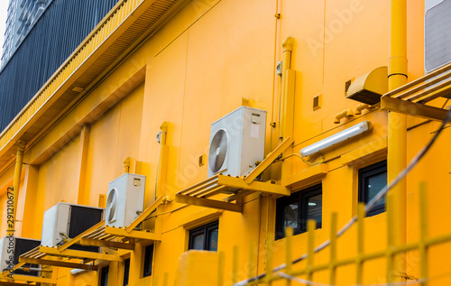 Modern air conditioner on a yellow wall. Air conditioning compressor   with black glass windows on the yellow wall building background.