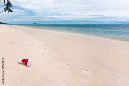 Santa Christmas hat in sand on a tropical beach. Holiday tropic summer concept. Thrown cap