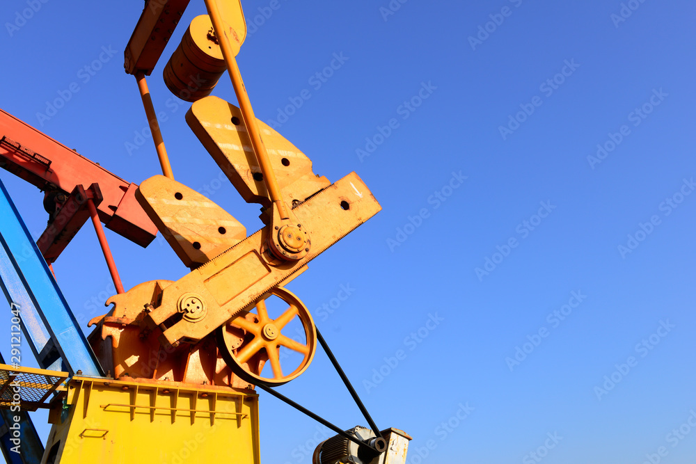 The beam pumping unit is working against the blue sky The beam pumping unit is working against the blue sky