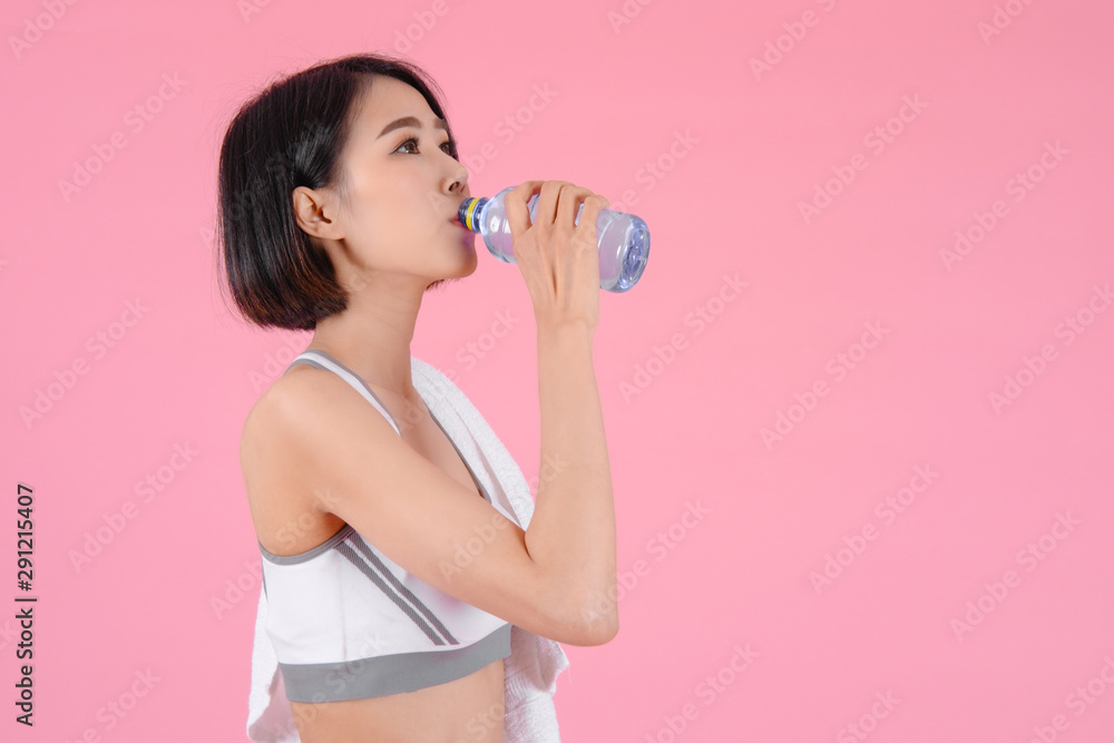 Healthy woman standing holdding water bottle and showing her beautiful body in home on pink backgrounds, Healthy concept, Diet concept Healthy woman standing holdding water bottle and showing her beautiful body in home on pink backgrounds, Healthy concept, Diet concept