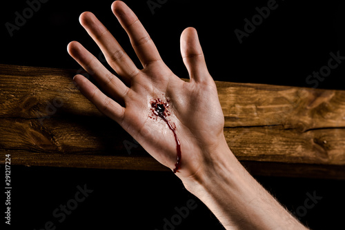 Fotografie cropped view of man crucified on wooden cross isolated on black