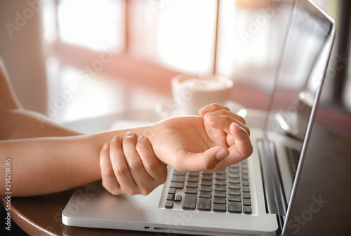 Woman holding her hand pain from using computer long time. Office syndrome concept.