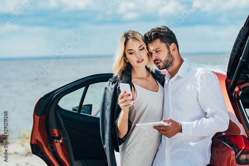 attractive woman using smartphone and handsome man holding digital tablet