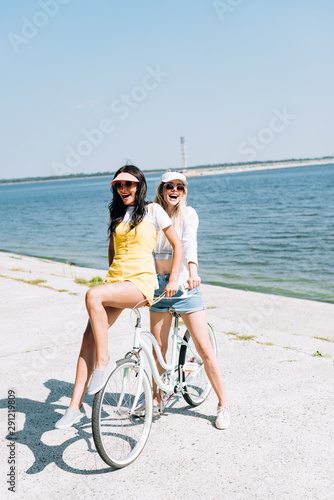 happy blonde and brunette girls with bike near river in summer © LIGHTFIELD STUDIOS