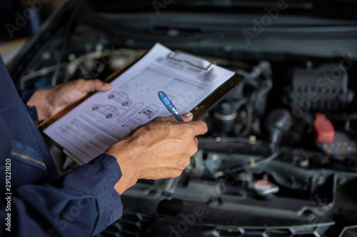 A mechanic service car in garage is check a list cars. photo