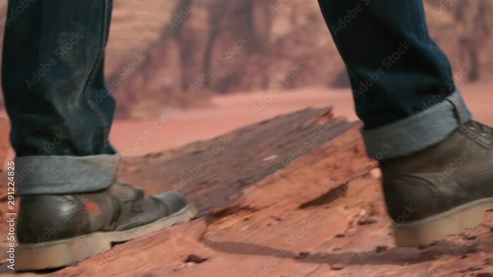 close-up of the feet of a man walking towards the edge of a cliff in the desert of wadi rum close-up of the feet of a man walking towards the edge of a cliff in the desert of wadi rum