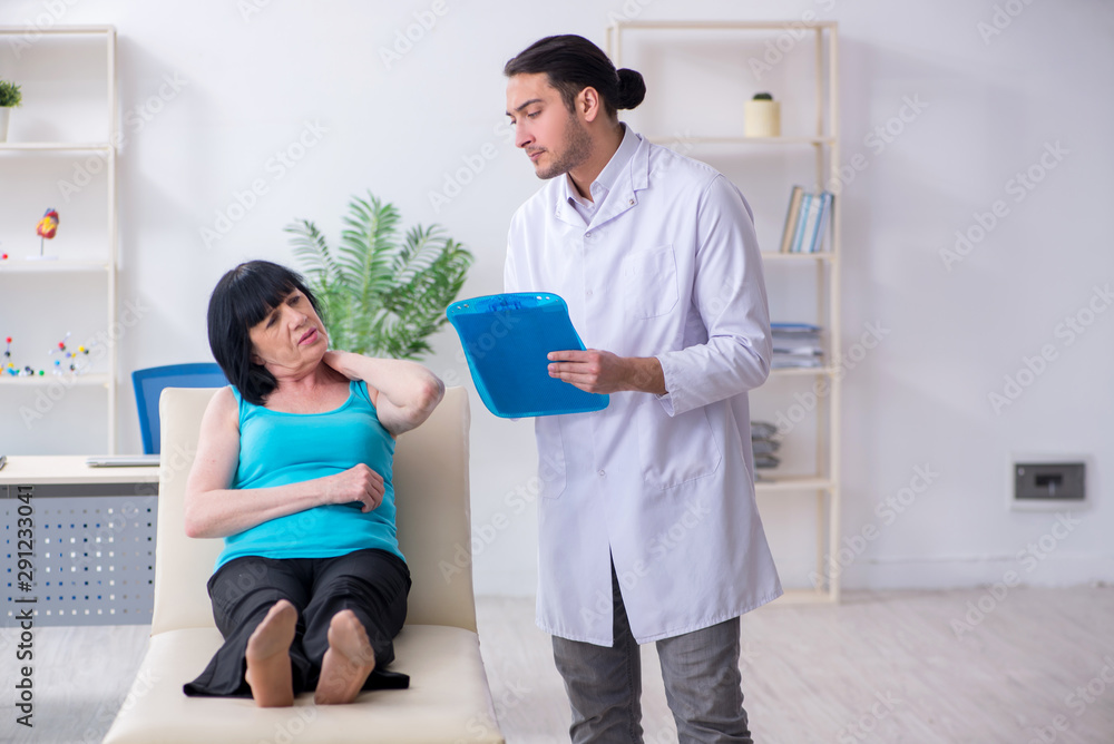 Fototapeta premium Young male doctor examining old female patient
