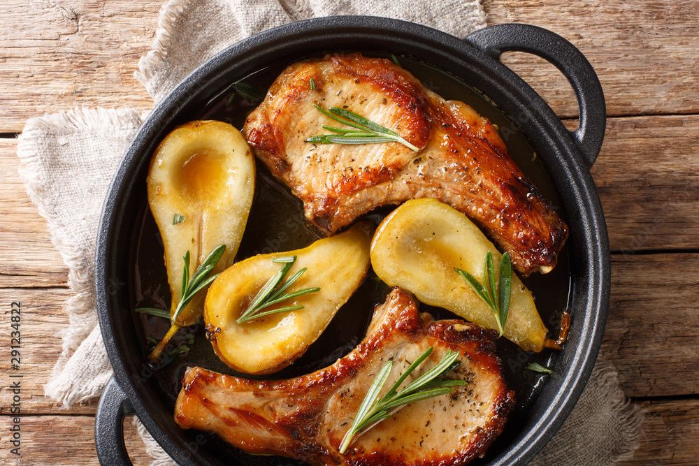 Holiday recipe for baked pork chops with pears and rosemary in honey sauce served in a pan close-up. Horizontal top view - obrazy, fototapety, plakaty 